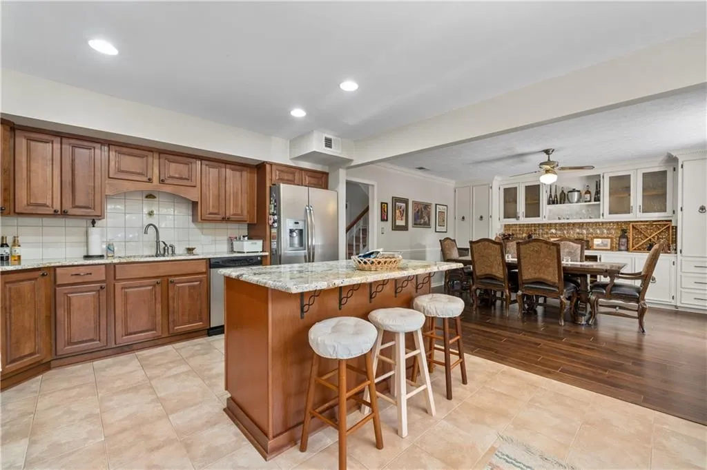 Kitchen featuring light hardwood / wood-style floors, backsplash, ceiling fan, a center island, and appliances with stainless steel finishes