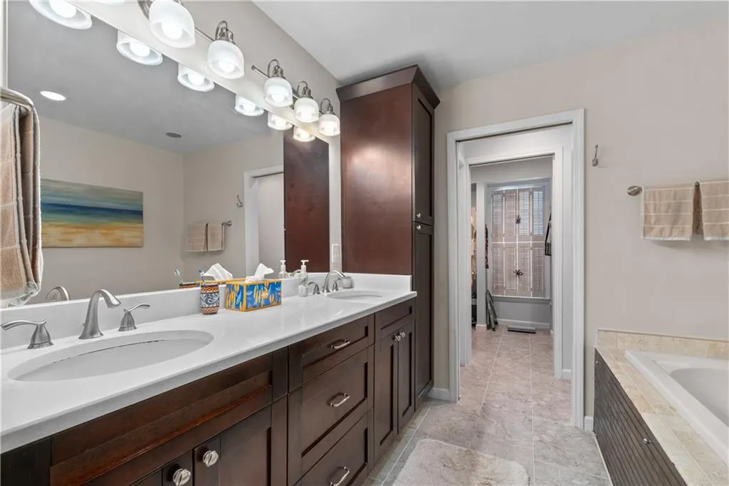 Bathroom with oversized vanity, dual sinks, tile floors, and tiled tub