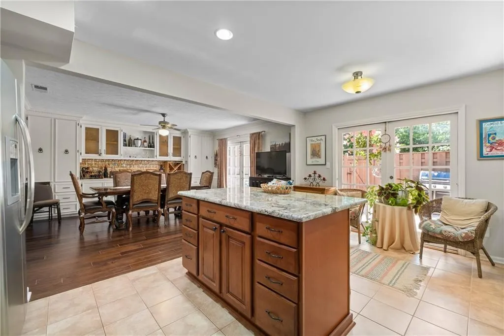 Kitchen with stainless steel fridge with ice dispenser, light hardwood / wood-style floors, ceiling fan, tasteful backsplash, and a center island