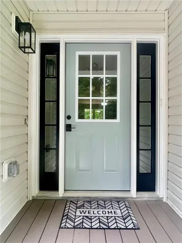 Entry door with upper paneled glass, flanked by vertical sidelight windows