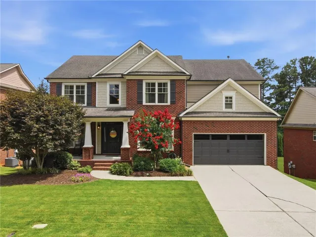 Traditional-style home featuring a brick facade, gabled rooflines, and a two-car garage with a concrete driveway