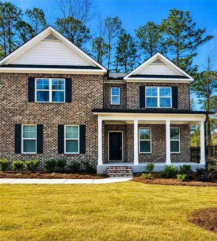 Brick facade featuring a covered porch with white columns, dark shutters, and a front entry door