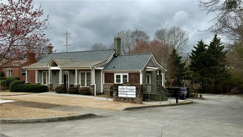 View of front of office with a chimney, a standing seam roof, and metal roof