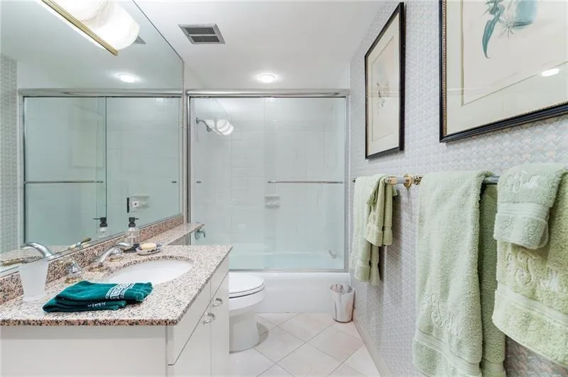 Full bathroom featuring shower / bath combination with glass door, visible vents, toilet, vanity, and tile patterned flooring