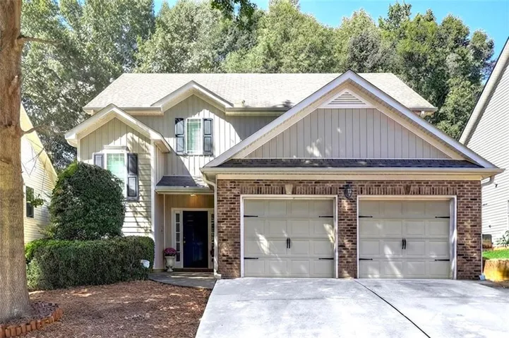 Two-story residence featuring brick and siding exterior, a two-car garage, and a covered front entry