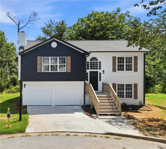 Contemporary split-level residence featuring a two-car garage, dark siding accents, and a prominent front entry with an arched transom window