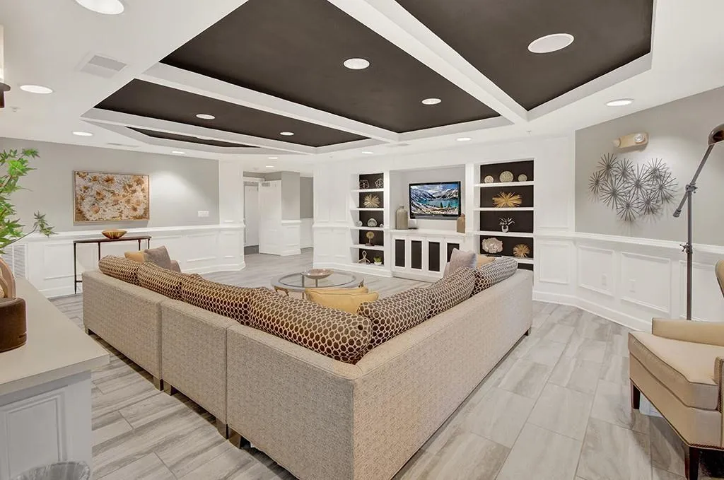 Living room with a tray ceiling, built in features, and decorative columns