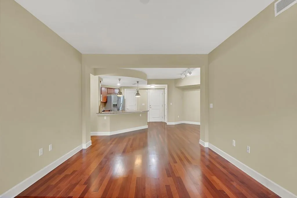 Unfurnished living room with a notable chandelier and dark wood-type flooring