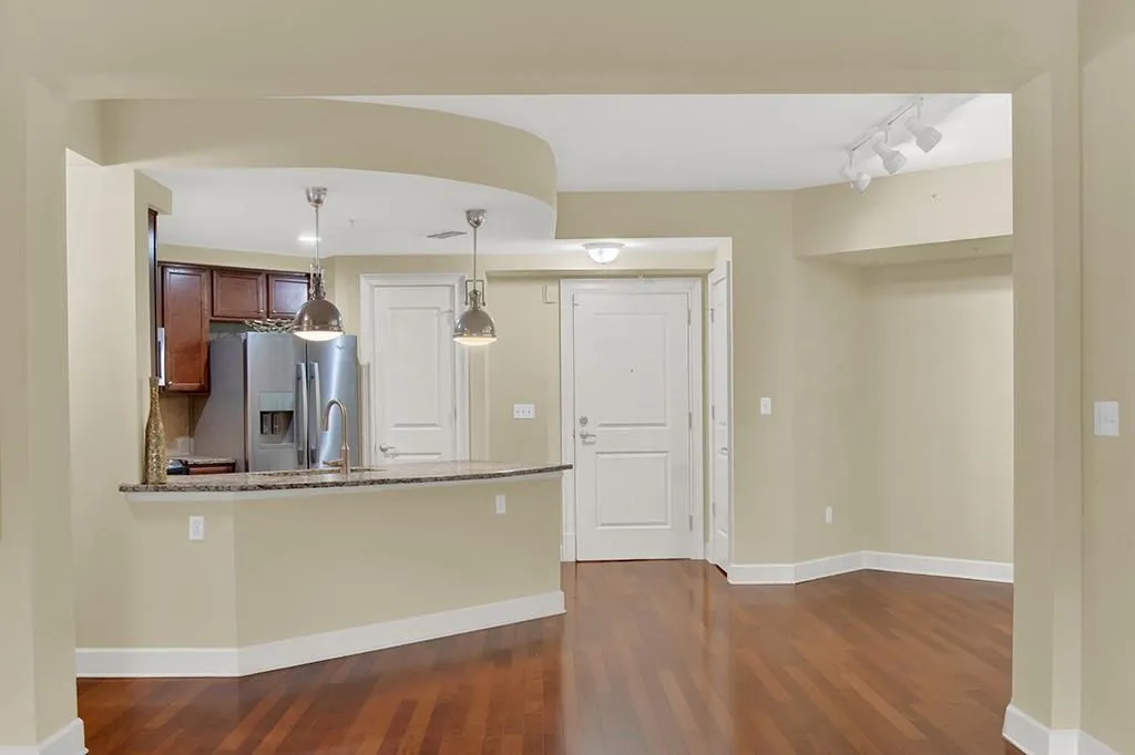 Kitchen featuring light stone countertops, dark hardwood / wood-style flooring, and stainless steel refrigerator with ice dispenser