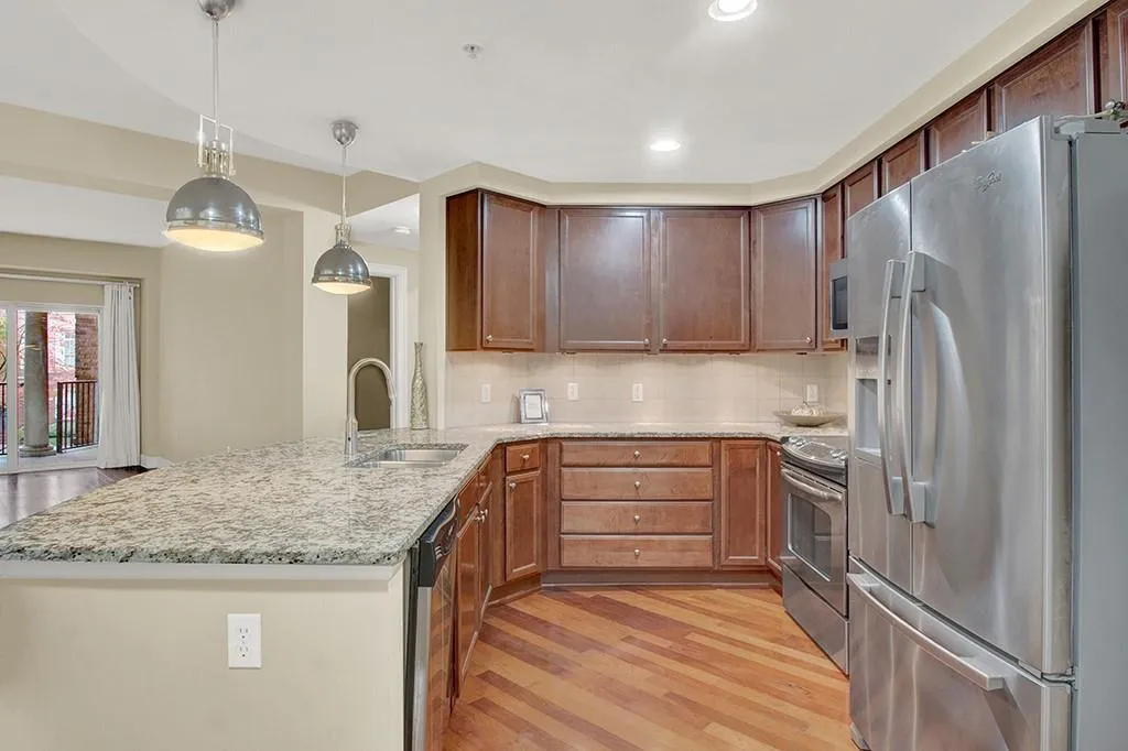 Kitchen with sink, light hardwood / wood-style floors, stainless steel appliances, tasteful backsplash, and decorative light fixtures