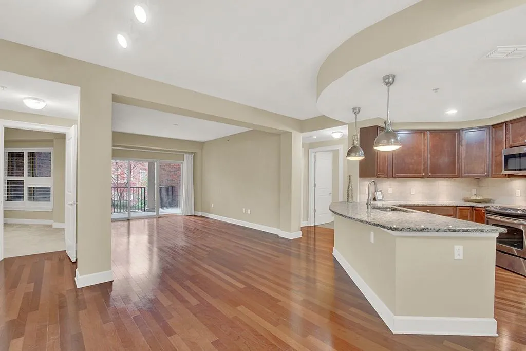Kitchen featuring tasteful backsplash, decorative light fixtures, dark hardwood / wood-style flooring, and light stone counters