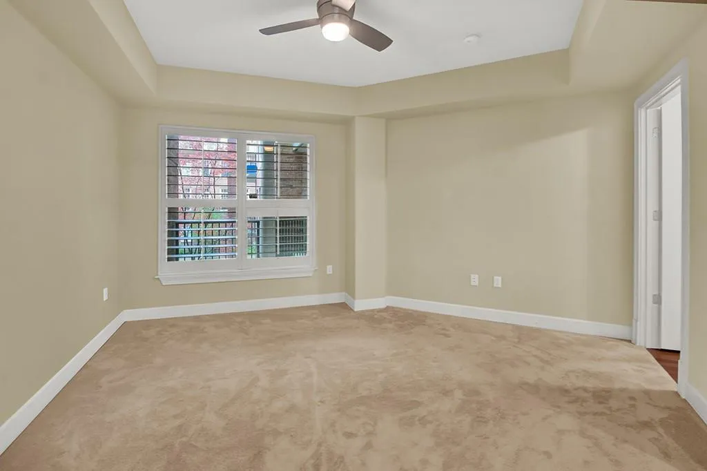 Carpeted empty room with a tray ceiling and ceiling fan