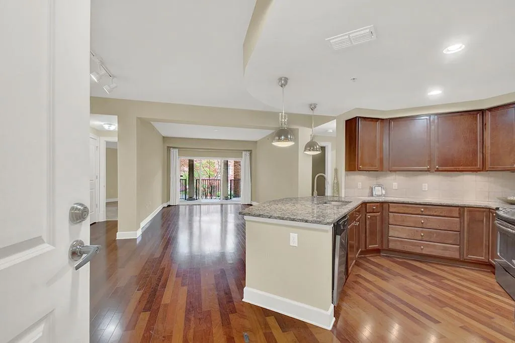 Kitchen with dark hardwood / wood-style floors, kitchen peninsula, sink, tasteful backsplash, and decorative light fixtures