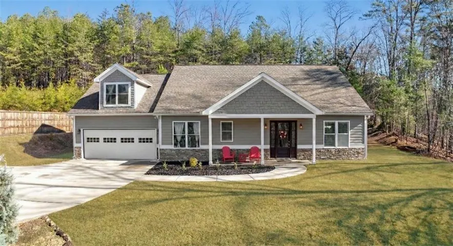 Craftsman-style home featuring a covered front porch, stone accents, and a two-car garage with a dormer window above