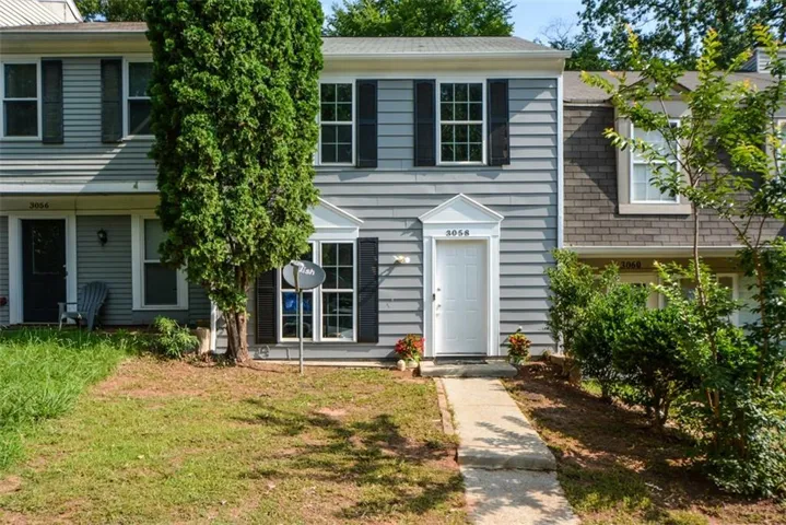 Gray siding facade with white entry door and architectural pediment