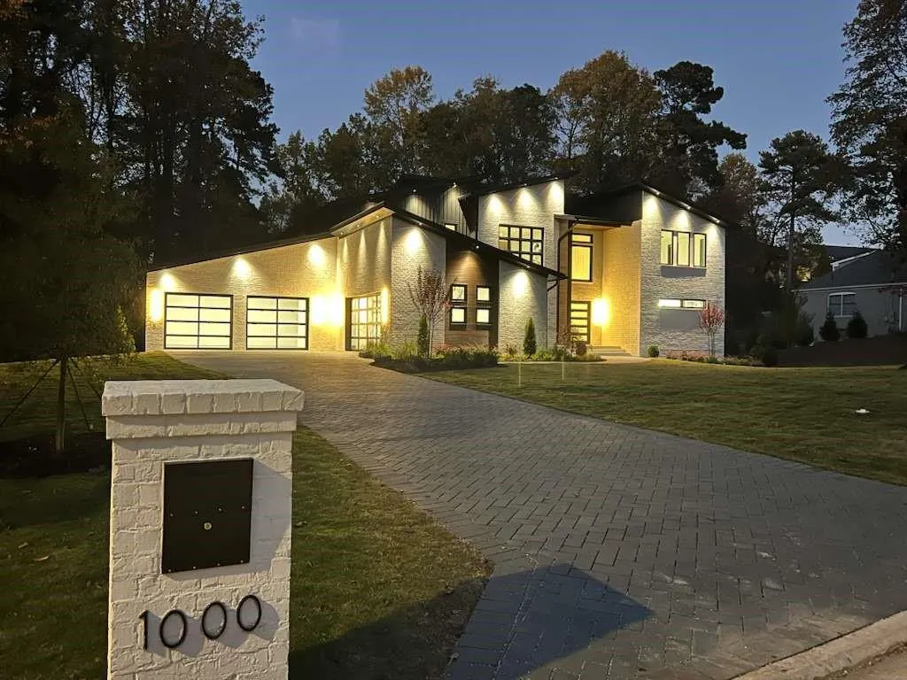 Modern home with stone siding, driveway, a front lawn, and an attached garage