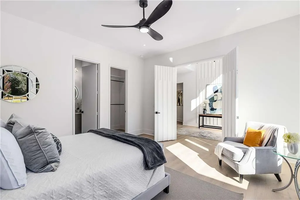 Bedroom featuring wood finished floors, ensuite bathroom, ceiling fan, and a walk in closet