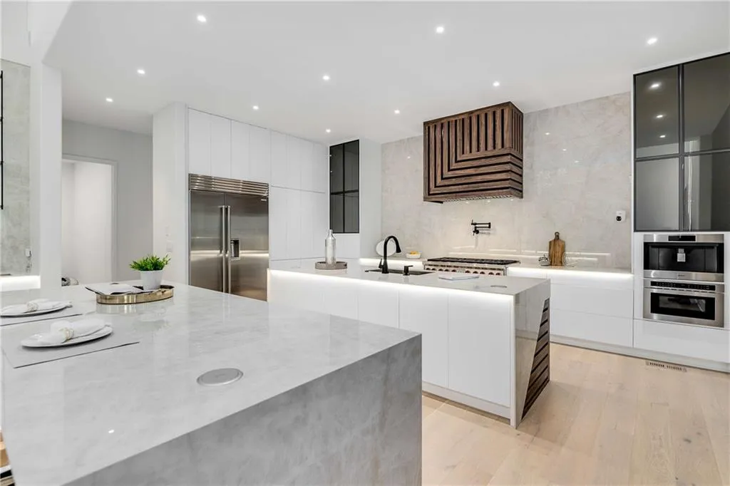 Kitchen with modern cabinets, built in fridge, recessed lighting, light wood-style flooring, and light stone counters