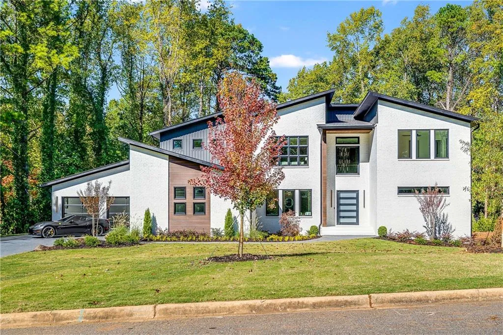 Mid-century inspired home with a front lawn, an attached garage, asphalt driveway, and board and batten siding