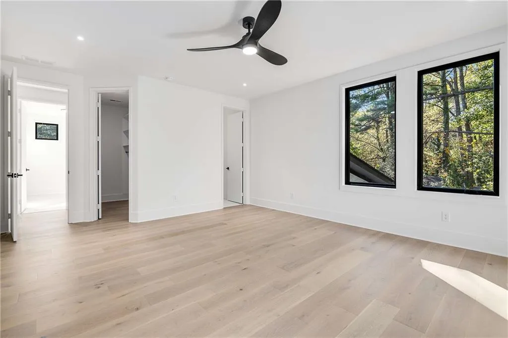 Unfurnished bedroom featuring a walk in closet, ceiling fan, light wood-type flooring, and recessed lighting