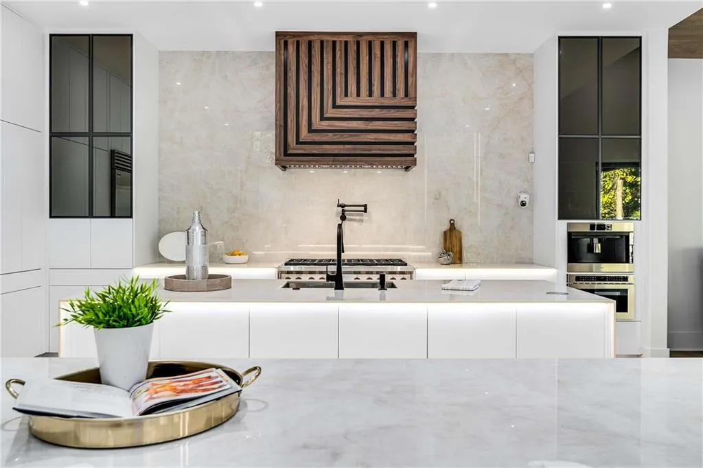 Kitchen with light stone counters, modern cabinets, stainless steel appliances, and white cabinets