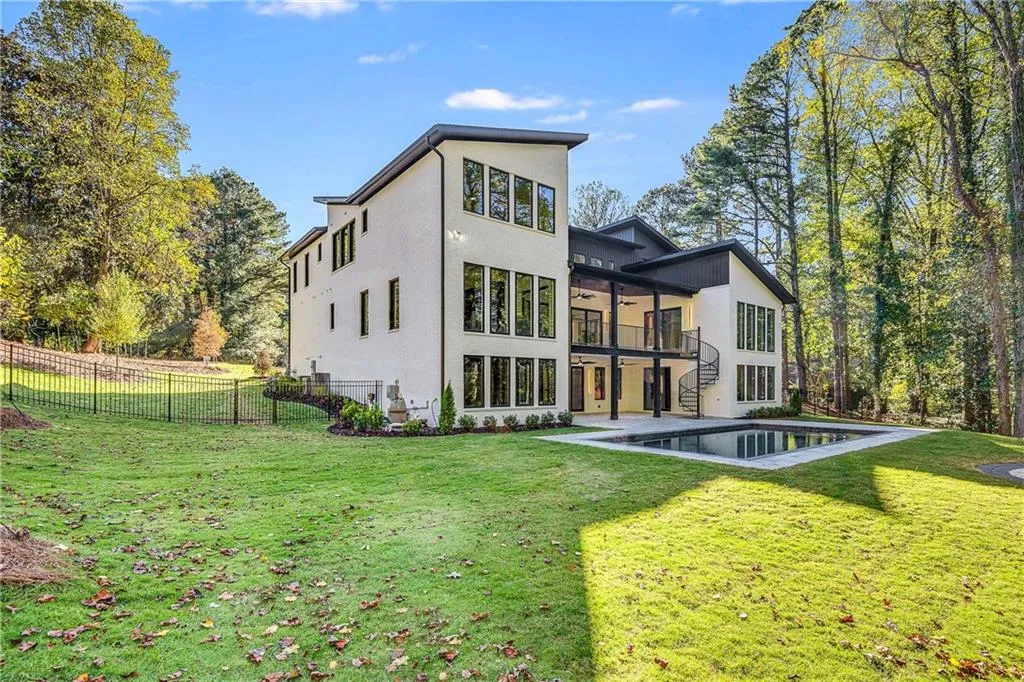 Back of property featuring a balcony, stucco siding, a patio area, ceiling fan, and view of wooded area