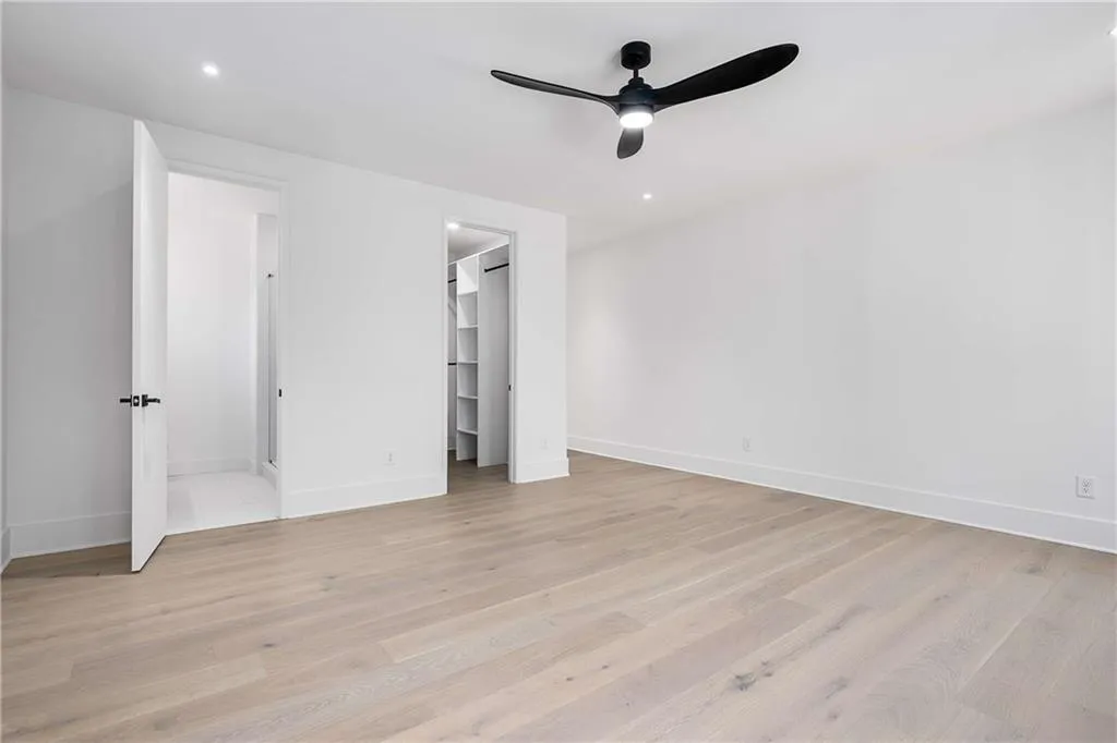 Unfurnished bedroom with a walk in closet, a ceiling fan, light wood-style flooring, and recessed lighting