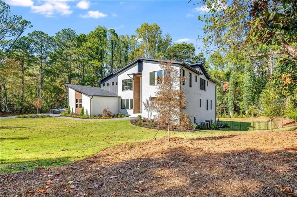 Rear view of house with stucco siding and view of scattered trees