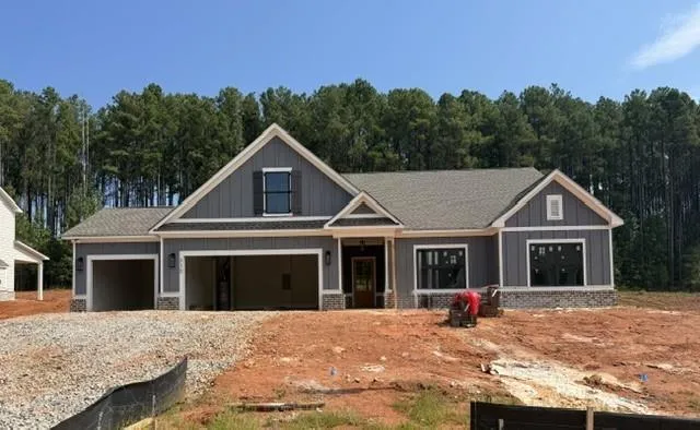 Craftsman-style exterior with gray vertical and horizontal siding, stone accent base, multi-pane windows, and a two-car garage