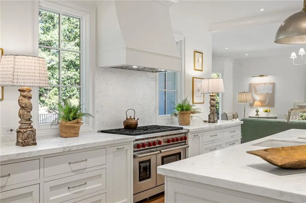 Kitchen featuring white cabinetry, stone-finish countertops, custom range hood, and stainless steel dual-oven gas range