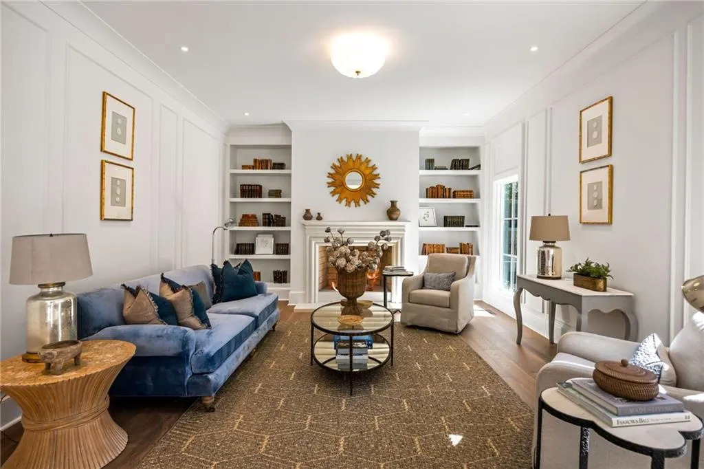 Living space featuring wall paneling, built-in recessed shelving, a fireplace with a decorative mantel, and wood-finish flooring