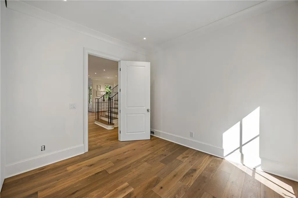 Room featuring wide-plank wood-finish flooring, crisp neutral wall paint, recessed lighting, and a multi-panel interior door