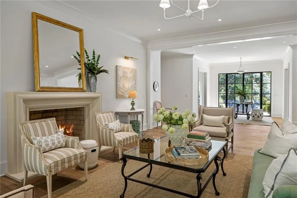 Stone-surround fireplace with hearth, wood-finish flooring, recessed ceiling lighting, metal-framed windows, and crown molding