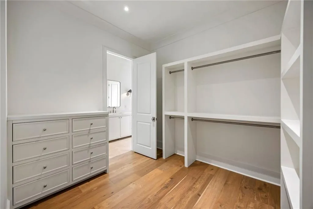 Custom built-in storage featuring white cabinetry, integrated drawer units, tiered shelving, and wood-finish flooring