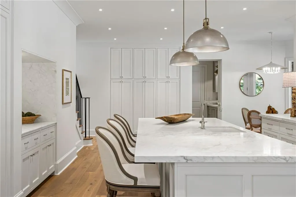 Kitchen featuring a central island with a stone countertop and an integrated sink, custom floor-to-ceiling cabinetry, wood-finish flooring, recessed lighting, and industrial-style pendant fixtures