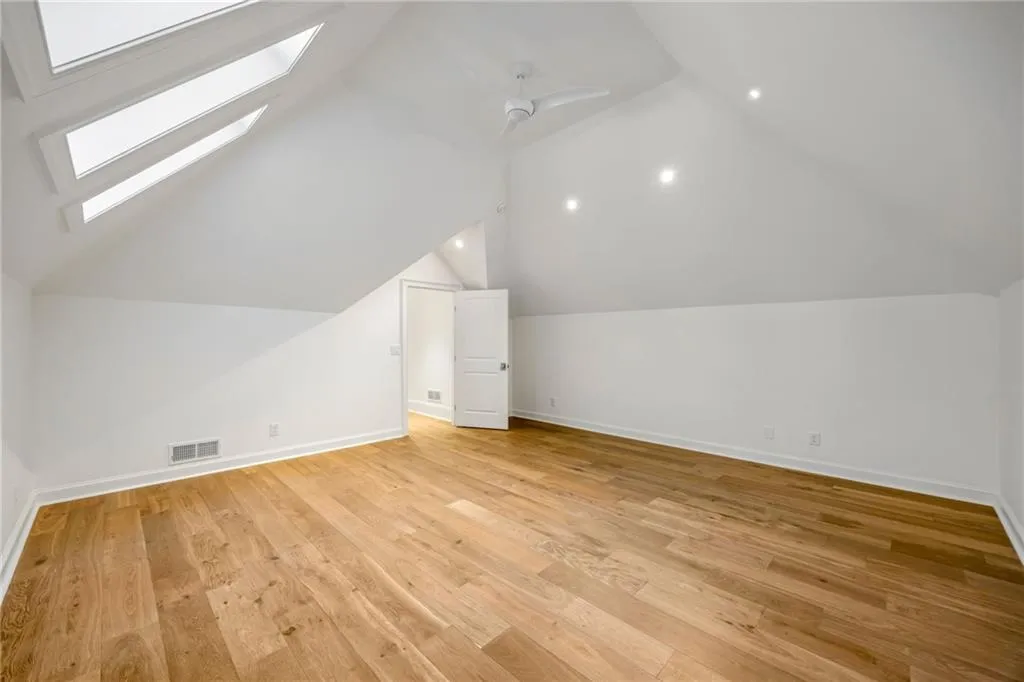 Vaulted ceilings featuring skylights, recessed lighting, a ceiling fan, and wood-finish flooring