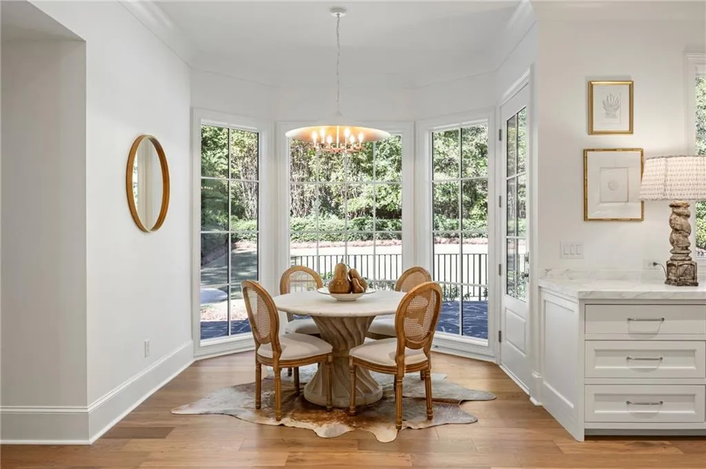 Bay window with floor-to-ceiling windows, wood-finish flooring, custom built-in cabinetry with stone-finish countertops, and a multi-light chandelier