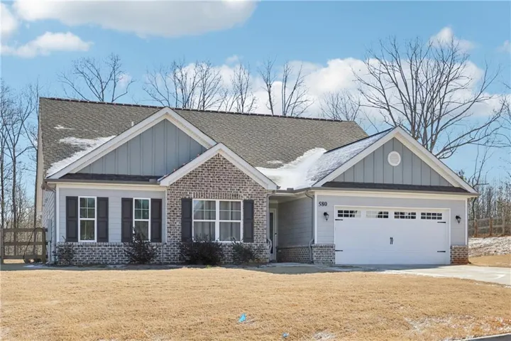 Craftsman-style house with board and batten siding, brick siding, a garage, concrete driveway, and a shingled roof