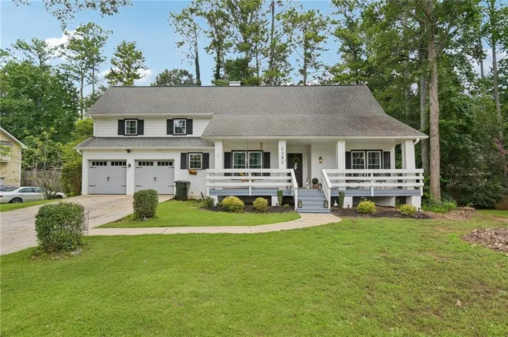 Two-story residence featuring a white facade, dark shutters, and a covered front porch with white railing