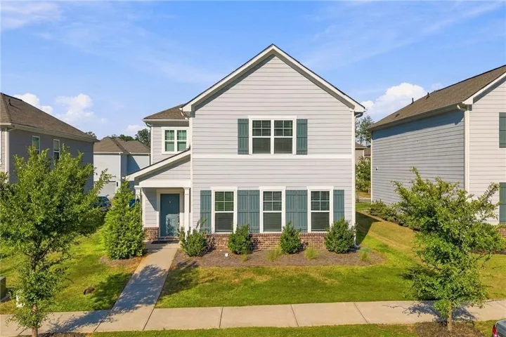 Two-story residence featuring light-colored siding, dark shutters, and a covered entry