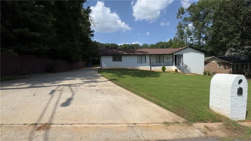 Single-story residence featuring a front lawn and paved driveway