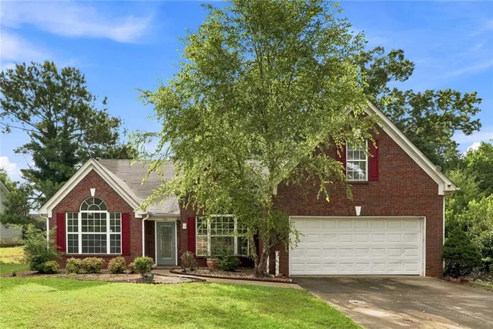 Brick-front residence featuring a two-car garage, red louvered shutters, and arched window details