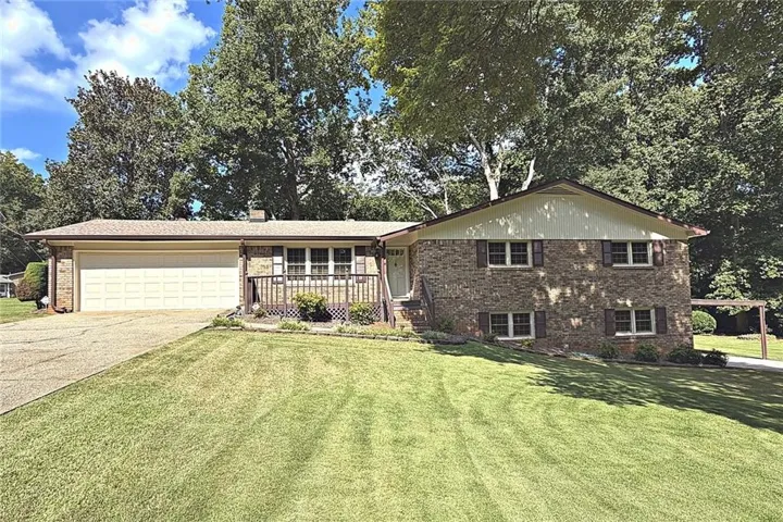 Brick and siding exterior with a two-car garage, front porch, and mature landscaping