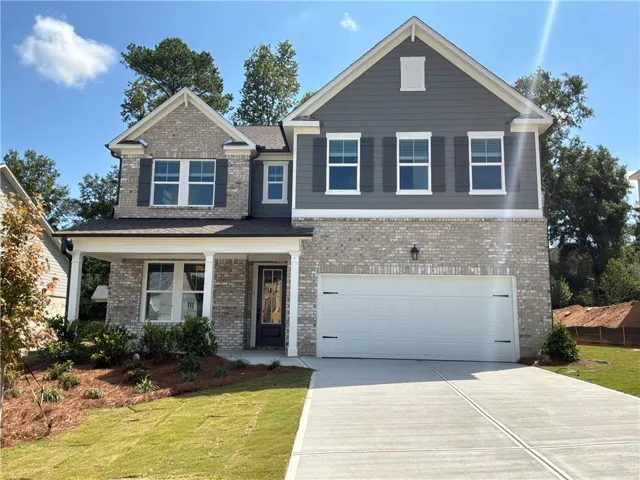 Striking two-story colonial featuring a brick and stone exterior with a gabled roofline and multiple upper-level windows