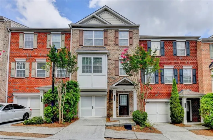 Brick facade with decorative shutters, integrated garages, and a prominent bay window