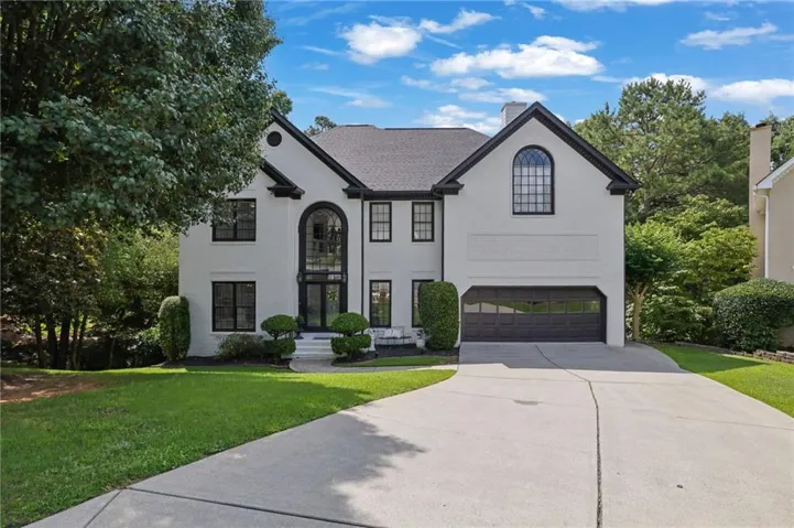 Contemporary white exterior with contrasting black trim, featuring a prominent arched two-story entry and a two-car garage