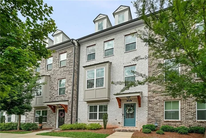 Brick and stucco exterior with multiple dormer windows, bay window, and gabled entry awnings