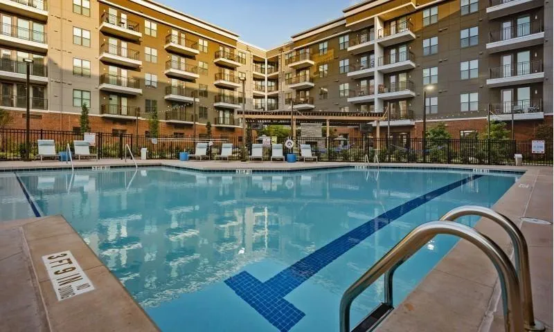 Outdoor swimming pool with tile accents, surrounding patio, and metal pool ladders