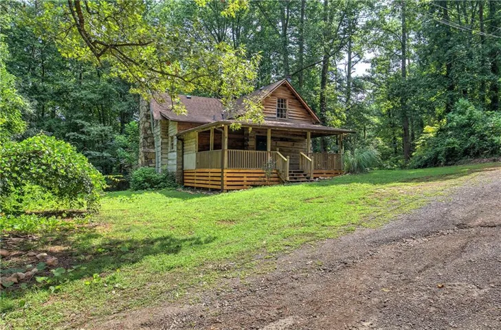 Rustic cabin featuring a covered front porch, log siding, and a stone chimney