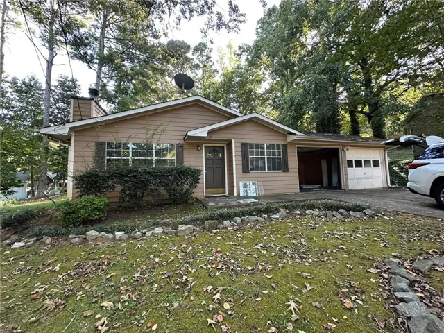 Single-story residence featuring a brown exterior, front entry door, multi-pane windows, and an attached garage